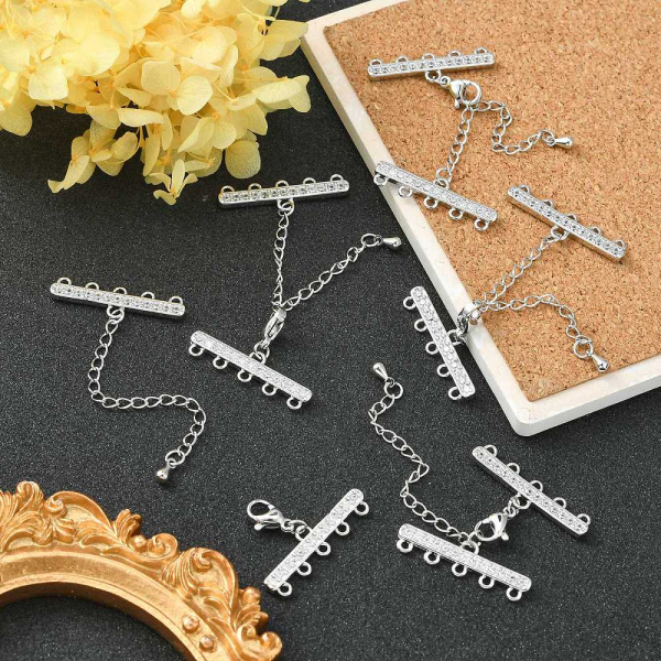 Застежка-карабин 10х6мм с удлиняющей цепочкой и соединителями-переходниками с пятью петельками 28х8мм, Milano, базовый материал - латунь, под родий <p>Элитная ювелирная фурнитура премиум класса - Милано люкс (Milano Lux), качественный элемент для создания бижутерии. Набор для окончания многорядного украшения или широкого плетёного браслета/колье. В набор входят 2 соединителя-переходника с 5 на 1 нить размером 28*8 мм, инкрустированных кристально-прозрачными стразами - фианитами (Cubic Zirconia – кубик циркония, CZ, цирконы). К одному концевику прикреплена застежка карабин (лобстер), к другому - цепочка-удлинитель длиной около 5 см. и декоративной капелькой на конце. В застёгнутом виде длина концевиком вместе с замочком (без учёта удлинителя) составляет около 28 мм. Цвет под родий. Оттенок может отличаться от фотографии и в разных поставках. При желании концевики можно отсоединить и использовать как коннекторы или подвески. Цена за 1 набор.</p>