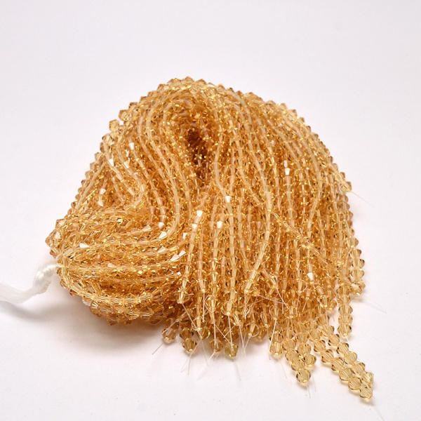 <p>Бюджетные стеклянные граненые бусины - биконусы янтарно-бежевого цвета. Бусины могут немного отличаться по форме и размеру. Оттенок может немного отличаться от фотографии и в разных поставках. Цена за низку около 85 бусин (низки формируются без проверки каждой бусины на дефекты).</p>