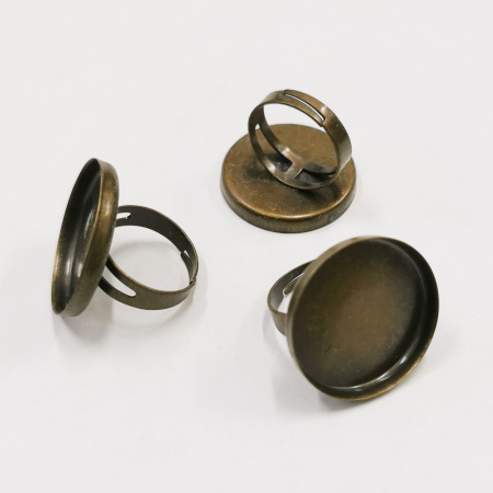 <p>Основа для кольца бронзового цвета с круглой платформой-чашей. Диаметр платформы - 25 мм. Высота бортика - около 3 мм. Кольца в разных поставках могут немного отличаться по дизайну: бывают с шириной кольца 5 мм, бывают раздвоенные у платформы и сужающиеся с 6 до 4 мм. Размер кольца регулируется. Оттенок может отличаться от фотографии и в разных поставках. Цена за 2 шт.</p>
<p>Внимание: возможны пятнышки, разводы, царапины; платформа может быть немного смещена относительно центра и припаяна под наклоном, платформа может быть чуть погнута.</p>